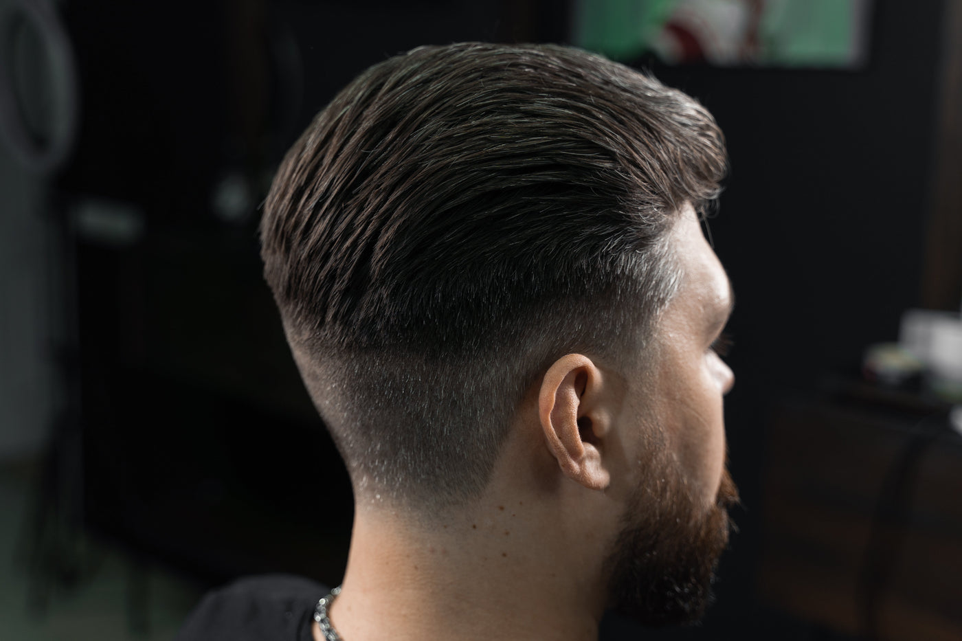 Barber giving a man a low fade machine haircut at a barbershop