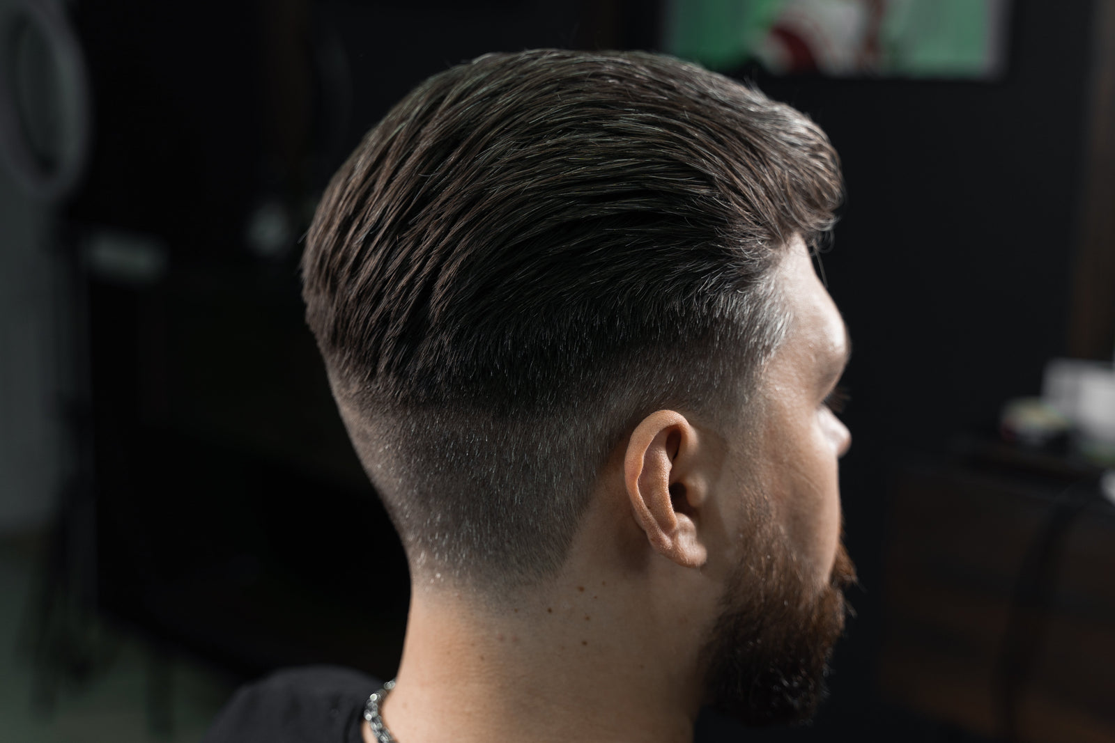 Barber giving a man a low fade machine haircut at a barbershop