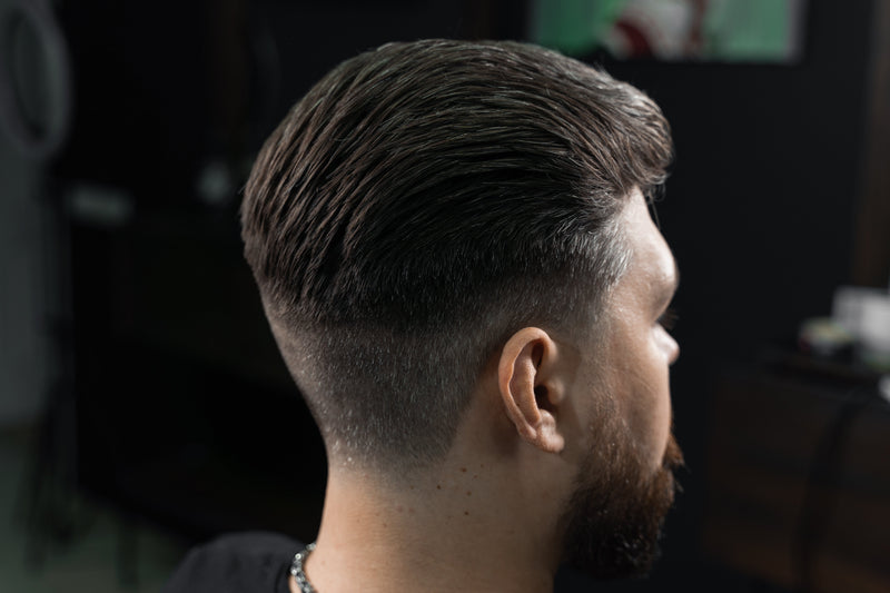 Barber giving a man a low fade machine haircut at a barbershop