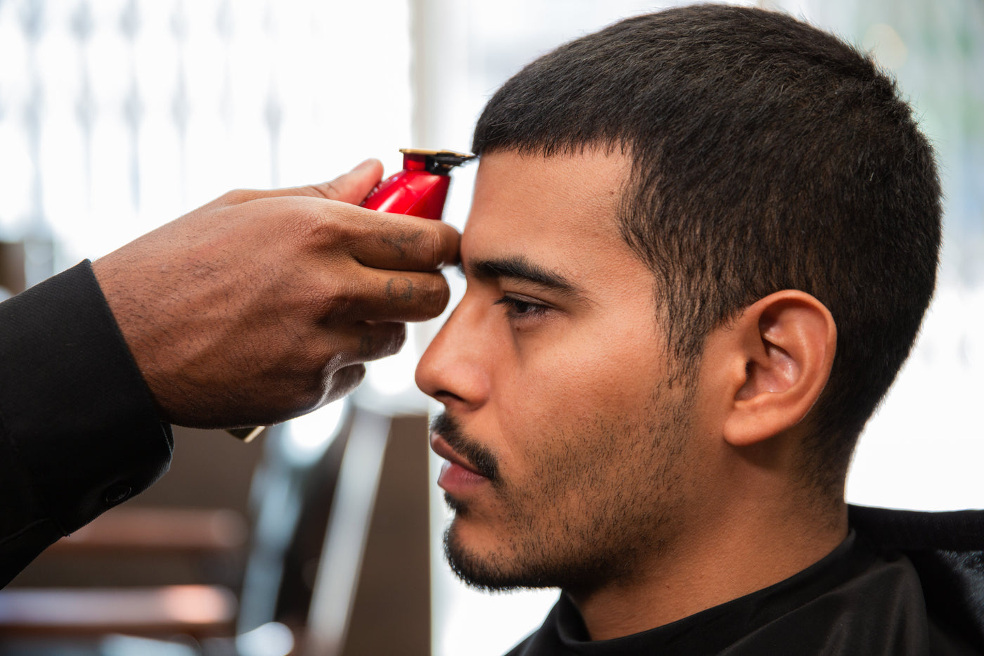 Barber using a razor to give a man a precise buzz cut