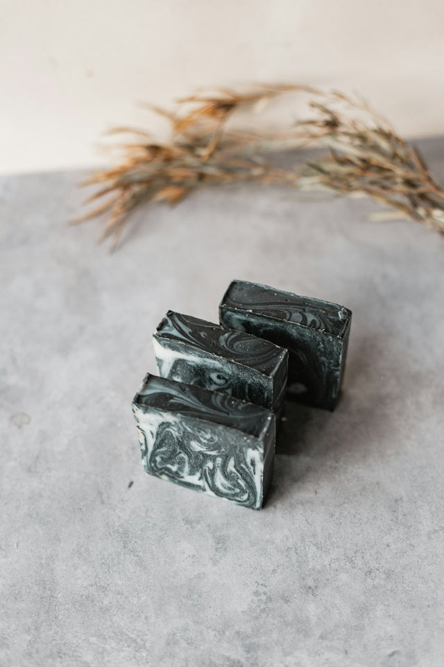 Marbled activated charcoal soap bars on a stone surface