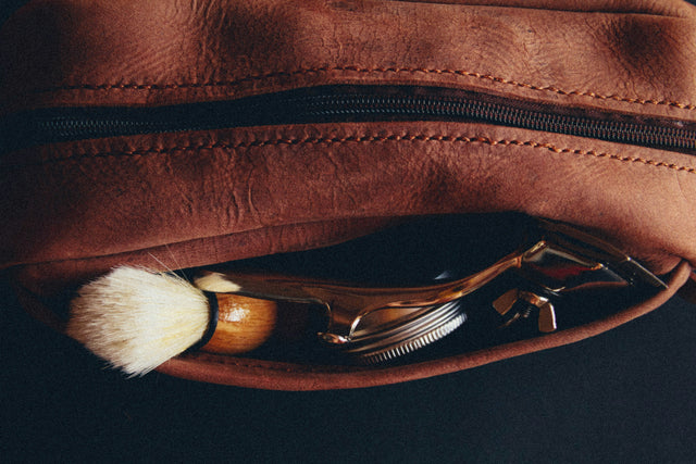 Leather toiletry pouch with a shaving brush and safety razor — a classic grooming kit, echoing Knightsmen's beard and hair growth starter kits