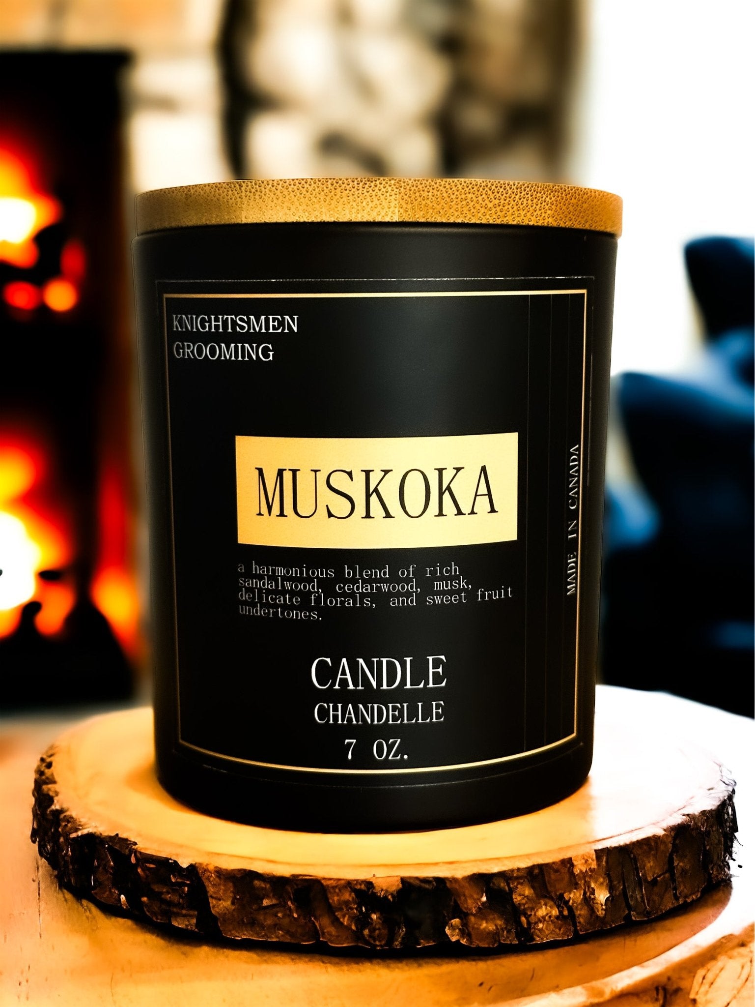 Muskoka candle in a black container with gold accents on a wooden coaster.