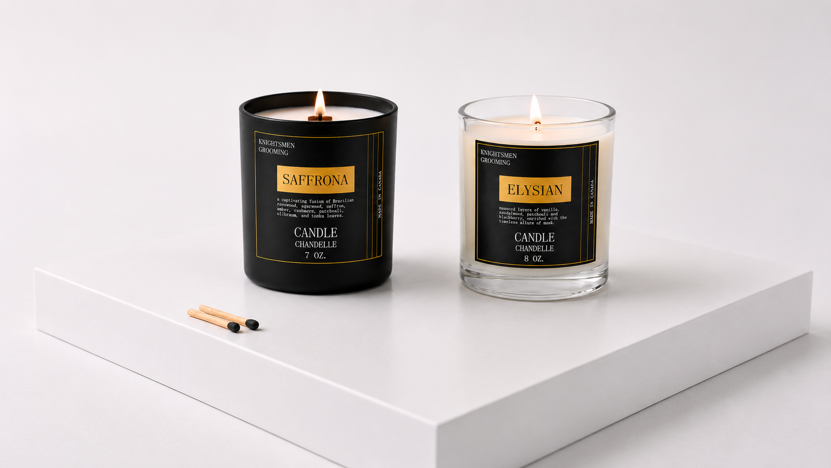 Two lit candles displayed on a white pedestal against a light gray background. On the left is a matte black jar candle labeled SAFERONA, and on the right is a clear glass jar candle labeled ELVIAN.